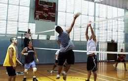 Ben Duong, CMSAPAC's right forward, pushes the ball up and over the hands of Robert O'Toole, Aches and Pains 2's center forward, during a 2008 Intramural Volleyball League game at the gymnasium July 24 here.