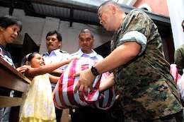 Hospital Corpsman 1st Class Eduardo Mojica, corpsman with 1st Marine Air Wing, hands a bag full of clothing and toys to a young Philippine girl on behalf of Operation Good Will during a civic military operation held in collaboration with Balikatan '09 at the Santo Nino Parish Church here April 22. More than 30 AFP and U.S. troops assisted with handing out over a ton of goods to needy Philiippine people in the area. (Photo by Lance Cpl Cristina Gil)