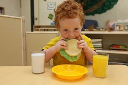Scotty Howard, a 2 year old in the Toddler 1 classroom at the New Hadnot Point Child Development Center, sits at a table and plays with some toys as he pretends to eat his burger.