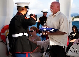 Staff Sgt. Raymond M. Shinohara, Marine coordinator for the interment ceremony, salutes Frank R. Cabiness’ flag after presenting it to his son, Jerry Cabiness, at the USS Arizona Memorial here Dec. 23. Although Frank Cabiness passed away in 2002, he was granted his final wish and rejoined his fallen comrades after being laid to rest inside the hull of the USS Arizona.