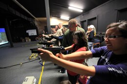 Marines assist spouses as they fire the M9 Beretta at the Indoor Simulated Marksmenship Training room during the Security Battalion's Jane Wayne Day on Camp Pendleton, June 23. Spouses also fired the M4 Carbine rifle and the M870 12 gauge shotgun.