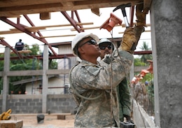 U.S. Army Spc. Duy Khuc hammers a frame Feb. 2 as Singapore Army Cpl. 1st Class Guru Prasad watches during construction of a new building at Ban Hua Wang Krang School, Muang District, Phitsanulok province, Kingdom of Thailand. Four similar structures are being built throughout the Kingdom of Thailand during ongoing engineering civic assistance projects part of Exercise Cobra Gold 2013. Exercise Cobra Gold includes humanitarian and civic assistance projects, a staff exercise and field training exercises. Joint and multinational training is vital to maintaining the readiness and interoperability of all participating military forces. Prasad is a combat engineer with the Singapore Army Combat Engineers. Khuc is a construction engineer with the 643rd Engineer Company (Vertical), 84th Engineer Battalion, 130th Engineer Brigade, Schofield Barracks, Hawaii.