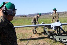 Sgt. Derrick Williams, left, communicates with the command center about wind calls as Sgt. Michael Lomartire, center, and Cpl. Andrew Smith, right, prepare the RQ-7B Shadow, an unmanned aerial vehicle, for a launch conducted here Feb. 27.
Williams was the plane captain and quality assurance chief for this exercise, and all of the Marines are UAV technicians from Marine Unmanned Vehicle Squadron 3 and VMU-4.
