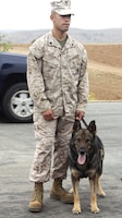 Sgt. Angelo Melendez, a Military Working Dog handler stands with his Military Working Dog during the unveiling of the Camp Pendleton War Dogs sign here July 20. The sign was made by Sgt. Adam L. Cann before he was killed in action by a suicide-bomb attack on an Iraqi police recruitment center.