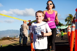 Lauren McMillen, a member of the Oahu community, crosses the finish line with her 7-year-old son, Liam, during the Camp Smith 5K Grueler here July 7.  The race, a part of the Commanding Officer’s Fitness Series, was open to service members, their families and the general public. 