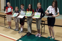 (From left to right) Holly Todd, Evelyn St. John, Brett St. John, Natalie Whatley, Trinity Wolfe and Julia Morgan present their award-winning posters during the annual Earth Day poster contest awards presentation at Elliott Elementary School, April 25. The contest aimed to teach kids more about their environment and with a theme of "Make every day, Earth Day," the top artists were rewarded with a certificate, medal and a gift card to the Marine Corps Exchange.