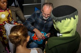 Fred Waring, station resident, passes out candy to the trick-or-treaters roaming the streets of Marine Corps Air Station Iwakuni, Japan, during the Halloween Festival Oct. 31, 2013. A total of 302 visitors came aboard station to partake in the festivities; 139 were adults.