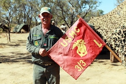 Arnold Beazley, a Salvation Army representative known as the Sallyman, holds the Lima Company, 3rd Battalion, 3rd Marine Regiment, Marine Rotational Force - Darwin, guidon during Exercise Koolendong, here, Sept. 4. Beazley delivers cold beverages and snacks to Australian soldiers and MRF-D Marines during field operations.