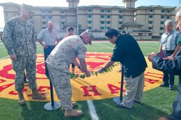 Col. Brian P. Annichiarico, commanding officer of Marine Corps Base Hawaii and Jon Shiota, manager of Semper Fit Center, ceremonially untie two maile lei during the reopening of Pop Warner Field, April 11. The space includes a calibrated rubber track and field turf with rubber infill to reduce injuries. 