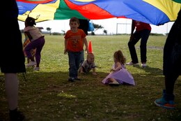 Children play beneath a parachute held up by Marine volunteers during an Easter egg hunt event for the families of Marines and sailors with Combat Logistics Regiments 35 and 37 April 13 at Roberts Field on Camp Kinser. Family readiness officers with the regiments organized the event to give all status of forces agreement personnel a way to enjoy the holiday. Both regiments are with 3rd Marine Logistics Group, III Marine Expeditionary Force. 