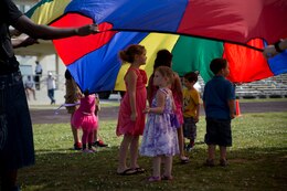 Children stand beneath a parachute held up by Marine volunteers during an Easter egg hunt event for the families of Marines and sailors with Combat Logistics Regiments 35 and 37 April 13 at Roberts Field on Camp Kinser. Family readiness officers with the regiments organized the event to give all status of forces agreement personnel a way to enjoy the holiday. Both regiments are with 3rd Marine Logistics Group, III Marine Expeditionary Force. 