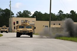 Clouds of charcoal-colored dust fill the streets as mock IED’s detonate, and the echo of machinegun fire adds to the realistic environment as Marines from Combat Logistics Battalion 2 are tested during a vehicle patrol August 20, 2014 in Holley Ridge, North Carolina.  While the IED’s and casualties were fake, the realistic scenarios helped the members of CLB-2 experience the physical and mental strains of dealing with an IED.  The training ensures the Marines are ready to employ counter-IED skills in any scenario.
