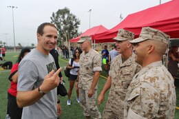 Drew Brees, left, New Orleans Saints quarterback and former San Diego Charger, greets Sgt. Maj. Richard Charron, right, Marine Corps Air Station Miramar sergeant major and Col. John P. Farnam, MCAS Miramar commanding officer, before the start of the NFL Football Star Experience aboard Marine Corps Air Station Miramar, Calif., July 15. Football players, like Brees, performed drills and signed autographs for service members and families aboard the air station. 