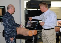 Roger Lankheet, simulation specialist, Staff Education and Training Department, briefs Surgeon General of the Navy, Vice Admiral Matthew Nathan about the ultra sound training device in the simulation center during a tour of Naval Hospital Camp Pendleton June 5, 2014.  The 440 square foot sim center features capabilities to provide realistic training for NHCP and area command medical staff members on adult and child mannequins. 