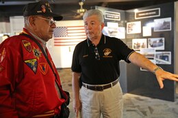 Retired Gunnery Sgt. Damaso Sutis (left), is given background information on Marine photographs by Ray Lebron (right), museum docent, aboard the depot, Feb. 21. The Iwo Jima veterans and their families were given a tour of the base by Marines of the depot.