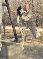 Marine Sgt. Michael Baldwin, Marine Corps Detachment, swings across a pit during the Physical Endurance Confidence course event.