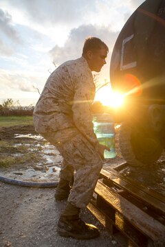 U.S. Marine Cpl. Colton Santic, with Combat Logistics Battalion 31, 31st Marine Expeditionary Unit, fills a water jug while Marines distribute water to local civilians during typhoon relief efforts in Saipan, Aug. 19, 2015. The Marines with Echo Company, Battalion Landing Team 2nd Battalion, 5th Marines, 31st MEU and CLB 31, 31st MEU, assisted the locals of Saipan by producing and distributing potable water. The Marines and sailors of the 31st MEU were conducting training near the Mariana Islands when they were redirected to Saipan after the island was struck by Typhoon Soudelor Aug. 2-3. (U.S. Marine Corps photo by Lance Cpl. Brian Bekkala/Released)