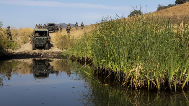 An internally transported vehicle and Marines from Company B, 1st Battalion, 1st Marine Regiment, 1st Marine Division prepare to ford a flooded road during an experimental exercise at Fort Hunter Liggett, Calif., Sept. 10, 2015. The experiment is designed to assist the Marine Corps warfighting Lab in capturing useful information in order for them to design a newer, more effective vehicle in the future. 